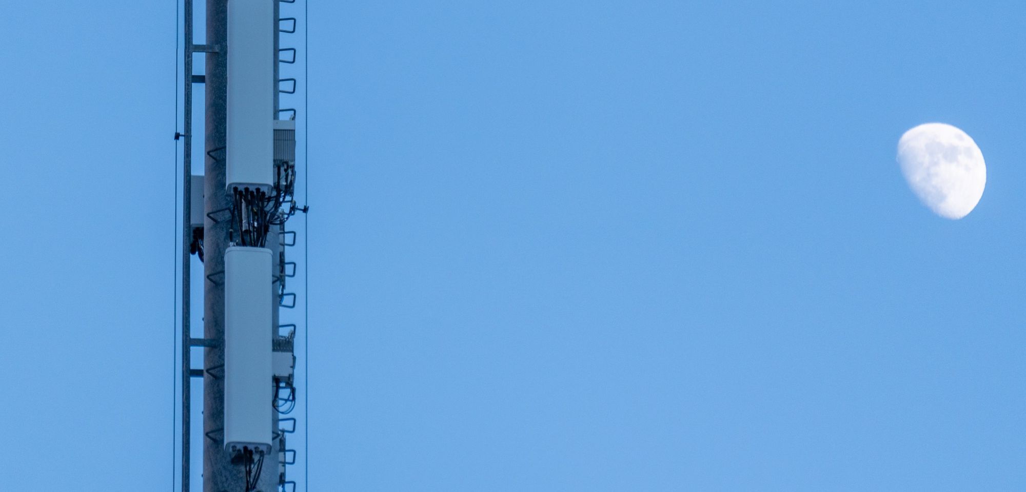 An LTE tower with the moon in the background. 